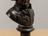 statue of a bust of a man sitting on top of a wooden table