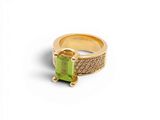 gros plan d'une bague en or avec une pierre verte