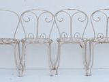 three white wrought chairs sitting next to each other on a white surface