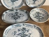 four blue and white plates with designs on them on a wooden table
