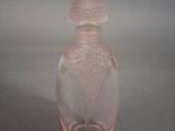 une bouteille en verre rose ornée d'un motif floral