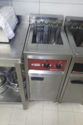 deux cuisinières en acier inoxydable dans une cuisine où des casseroles et des poêles sont posées sur le plan de travail