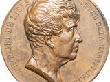 an old bronze medal with a woman ' s profile on it