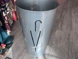 a metal trash can with an umbrella on the floor