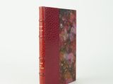 l'image d'un livre à la couverture rouge posé sur une surface blanche