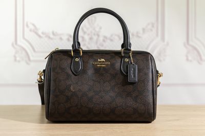 un sac à main marron de la marque Coach posé sur une table en bois