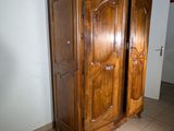 a large wooden armoire in a room with tile flooring