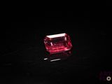 un diamant rose sur une surface noire dans l'obscurité