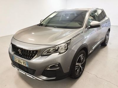 Une voiture argentée est garée dans une pièce blanche