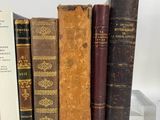 several old books are lined up in a row on a shelf
