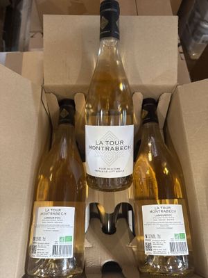 trois bouteilles de vin blanc dans une boîte en carton posée sur une table