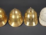 three brass helmets are lined up against a black background