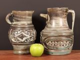 two vases sitting next to a green apple on a table