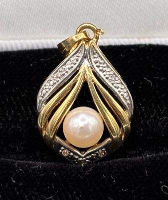 a close up of a gold and silver pendant with a pearl in it