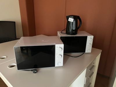 two microwaves sitting on top of a white table