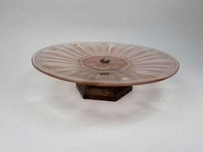 assiette à gâteau en verre rose posée sur un support, sur une surface blanche, avec un fond blanc