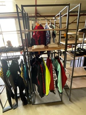 a rack of clothes in a room with a lot of shelves