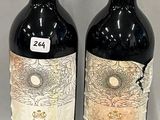 two bottles of red wine sitting next to each other on a table