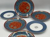 six assiettes bleues et rouges ornées de motifs, posées sur une table