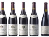 six bottles of wine are lined up on a white surface