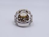 a close up of a silver ring with a yellow stone in it