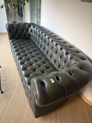 a black leather couch sitting on a hard wood floor