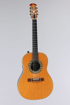 an acoustic guitar on a stand against a white background