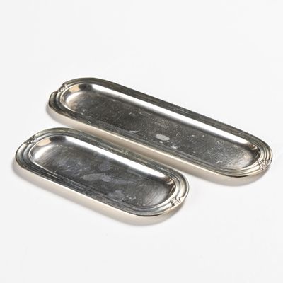 two silver metal trays sitting on top of a white surface