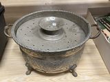 a large metal pot with a lid on a wooden table