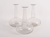 trois vases en verre transparent posés sur une surface blanche