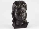 sculpture représentant la tête d'une femme aux longs cheveux sur fond blanc