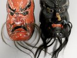 two black and red masks with long hair on a white surface