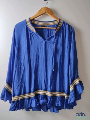 an image of a blue blouse hanging on a hanger on a wall