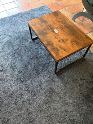 une petite table en bois sur laquelle est posé un ordinateur portable, dans un salon