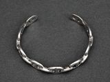 a close up of a silver bracelet on a black surface