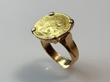 a close up of a gold ring with a coin on it