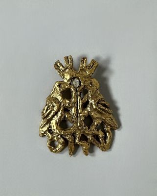 a close up of a gold brooch with a bird on it