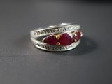 une bague en argent ornée de pierres rouges et de diamants, posée sur une table