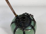 an image of a green and black vase with a wooden stick sticking out of it
