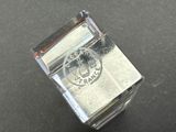 a clear glass box with a silver stamp on it