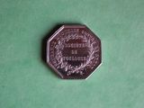 une pièce d'argent posée sur une surface verte, sur laquelle figure une image