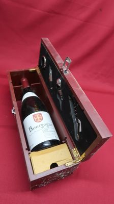 a bottle of wine in a wooden case on a red cloth
