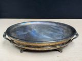 an old silver plate with a handle on a wooden table