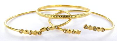 three gold rings with diamonds on them on a white surface
