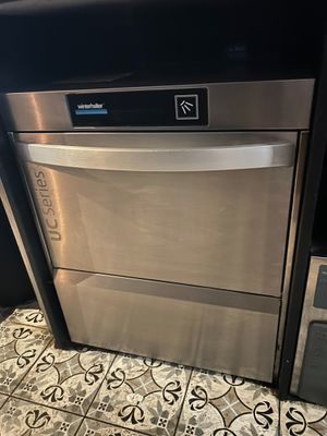 a silver dishwasher sitting on a tiled floor in a kitchen