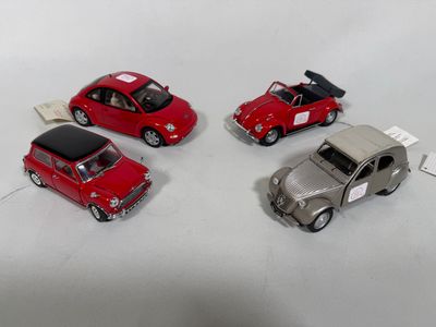 four miniature cars that are sitting on a white surface