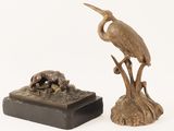a bronze statue of a bird on a tree stump next to a bronze sculpture of a dog