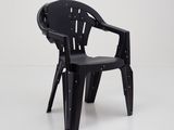 une chaise en plastique noire posée sur un sol blanc