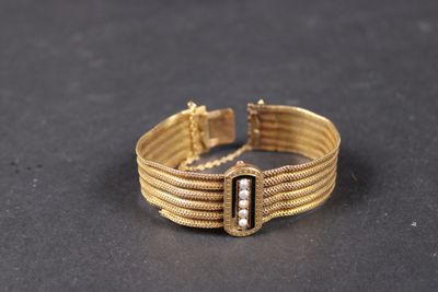 gros plan d'un bracelet en or sur une surface noire