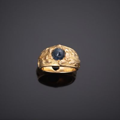 gros plan d'une bague en or avec une pierre bleue